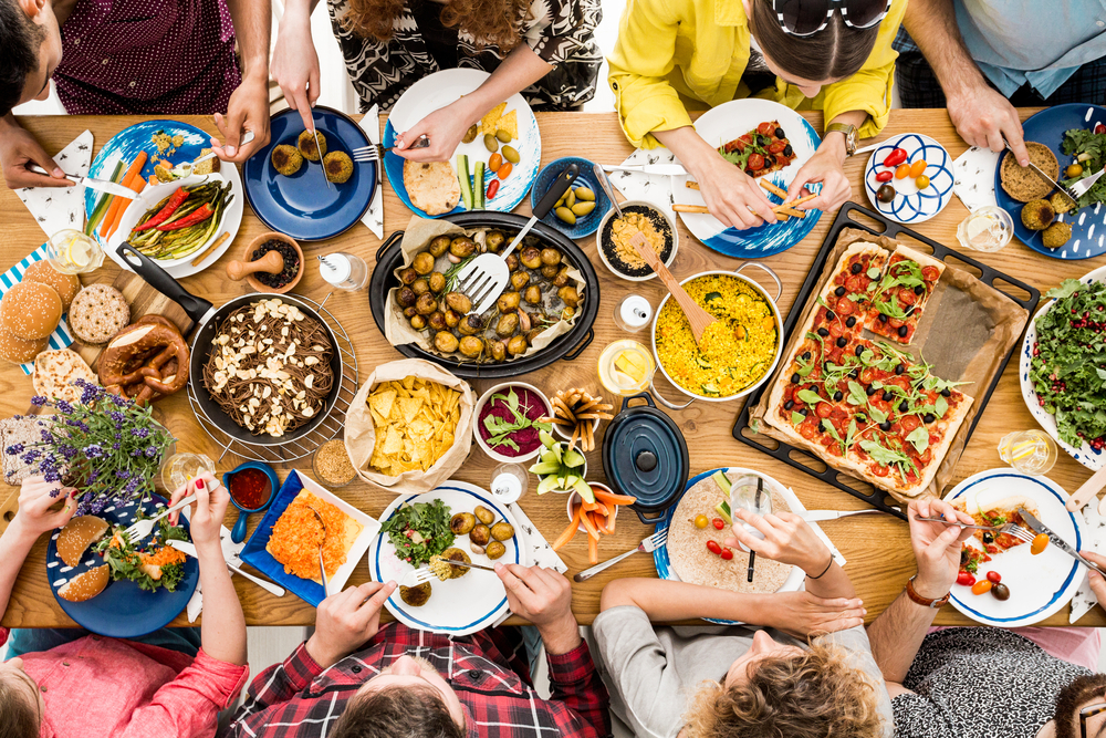 Friends gather over alternative proteins and other dishes for a vegan meal.